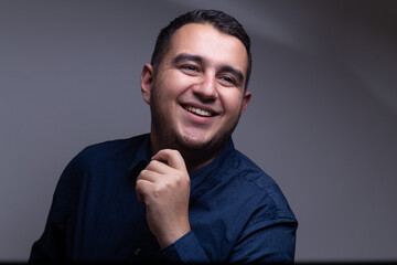 hombre profesional con camisa azul sonriente frente a un fondo blanco 