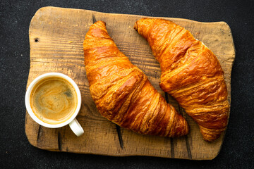 Croissant and coffee at black background. French pastry, bakery, fresh dessrt. Top view.