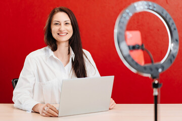 a brunette woman works at the computer and conducts a live broadcast 