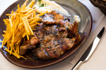 Plate of grilled lamb meat served with fried potato straws and sauce