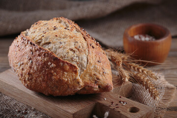 Fresh baked whole grain bread with oats, flax seeds and sesame seeds on rustic wooden board. Bakery...