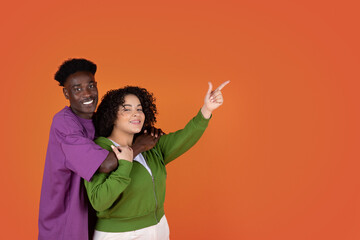 Cute multicultural couple embracing and showing free space