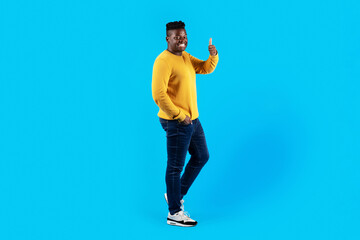 Fototapeta na wymiar Black Man Showing Thumb Up At Camera While Standing Over Blue Background