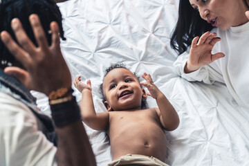 Afro-American little kid laying on the bed and playing with his parents, leisure time. High quality photo
