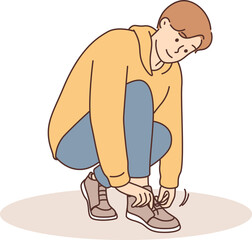 A little boy ties a shoelace on his shoe