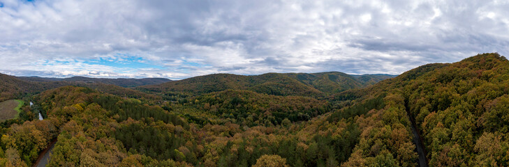 Fototapeta na wymiar Panoramic Aerial View view of mountain hills. Hilltops covered with autumn forest.