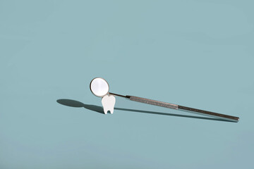 A model of a tooth with a dentist's dental mirror. The concept of dental hygiene and prevention of dental diseases