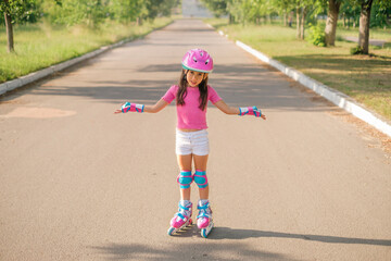 A disappointed girl in a protective sports helmet and roller skates throws up her hands. The child...