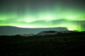 Naklejka na ściany i meble Extremely bright aurora borealis over snowy moutains, Iceland