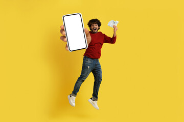 Happy indian guy jumping up with phone and money cash