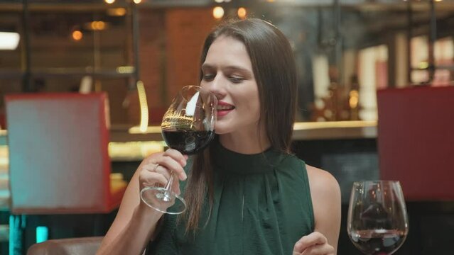 Beautiful woman having wine, smiling and chatting with boyfriend while having romantic dinner in restaurant