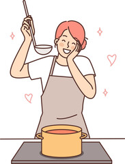 Happy housewife woman cooks soup standing at stove with saucepan and tastes after adding spices