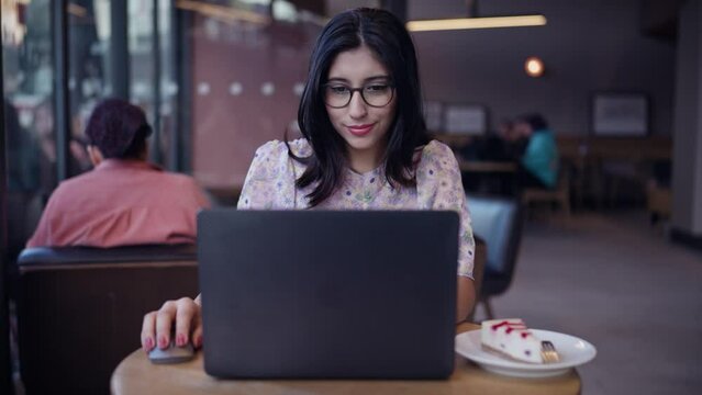 Nice multi race brunette beautiful young woman. Female portraits. Sitting at table in cafe. Female sitting in front open laptop computer. Study, learning, remote work, freelance.