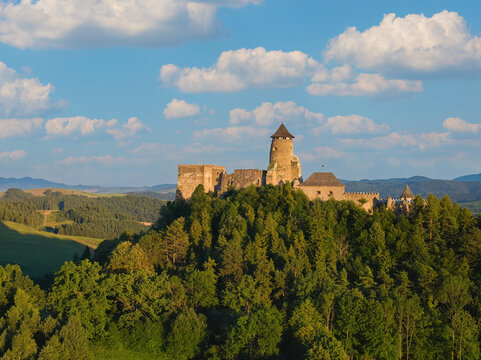 Lubovna Castle, Spis area, Slovakia. Medieval border castle, situated on a rock above wooded hills against blue sky, white clouds, summer. Travelling through the sights and castles of Slovakia.