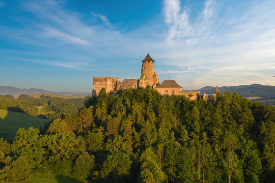 Lubovna Castle, Spis area, Slovakia. Medieval border castle, situated on a rock above wooded hills against blue sky, white clouds, summer. Travelling through the sights and castles of Slovakia.