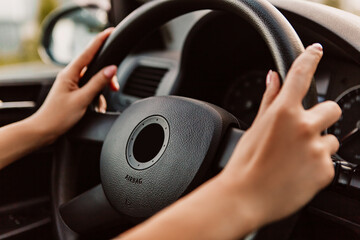 Close up woman driving car hold steering wheel, black dark car interior. Dashboard with speedometer...