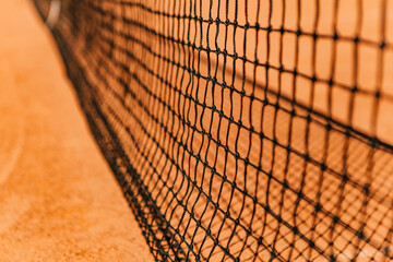 Light orange empty outdoor clay court surface dry grungy ground baseline detail for playing tennis with net in sunny day, gravel texture background, copy space for text inscription banner  © Volodymyr