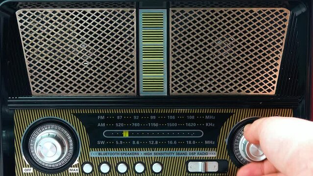 A Female Fingers Tuning the Frequency on an Old Vintage Analog Receiver.  Search for a music radio station on a dial scale on panel of a short-wave portable FM radio.