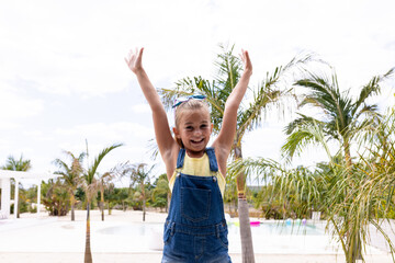 Portrait of happy biracial girl smiling by the swimming pool - obrazy, fototapety, plakaty