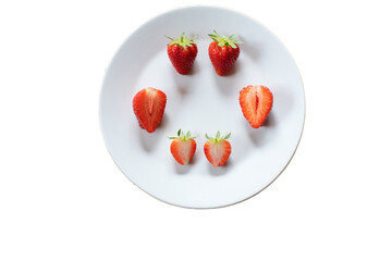 White plate with cut and whole juicy red ripe strawberries with leaves