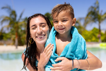 Portrait of happy biracial mother and son smiling by the swimming pool - obrazy, fototapety, plakaty