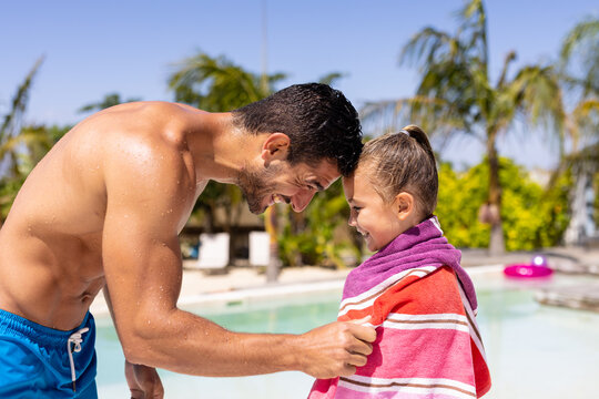 Happy biracial father and daughter using towel by the swimming pool - Powered by Adobe