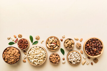 mixed nuts in wooden bowl. Mix of various nuts on colored background. pistachios, cashews, walnuts, hazelnuts, peanuts and brazil nuts - obrazy, fototapety, plakaty