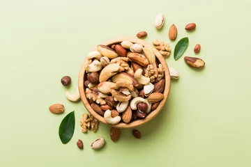 Fotobehang mixed nuts in bowl. Mix of various nuts on colored background. pistachios, cashews, walnuts, hazelnuts, peanuts and brazil nuts © sosiukin