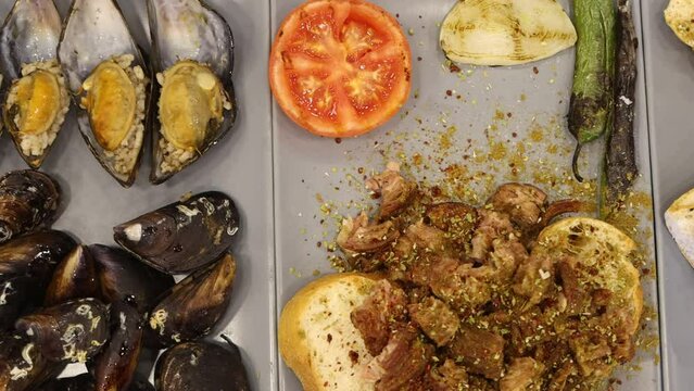 Turkish style appetizer street food stuffed mussels called midye dolma with lemon , Turkish kokorec and sucuk. High quality 4k footage