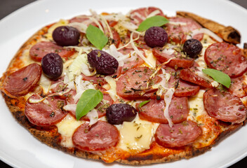 Traditional rustic pizza with pepperoni, black olives, onion and basil