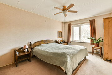 a bedroom with a bed, dresser and ceiling fan in the middle of the room there is a window that...