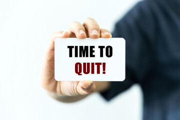 Time to quit text on blank business card being held by a woman's hand with blurred background. Business concept about the time to quit or stop bad habits or addiction.