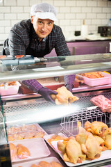 Male butcher showing fresh whole chicken in butchery