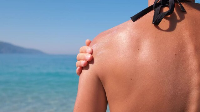 Woman apply sun cream on luxury beach. A woman applying sun cream on her skin to protect from sun on the sunny luxury beach.