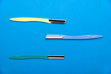 multi-colored women's razors with plastic handles on a blue background. Space for text.