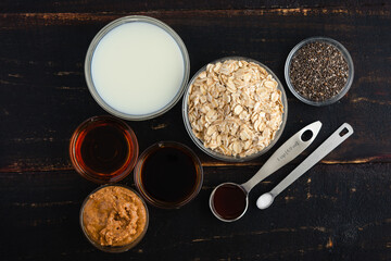 Vanilla Cold Brew Overnight Oats on a Rustic Wooden Table: Rolled oats, chia seeds, milk, and other oatmeal ingredients on a dark background