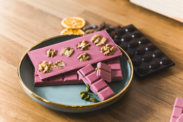 Candy shop concept. Plate full of pink ruby chocolate with walnuts and dark chocolate used for...