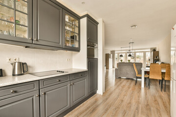 a kitchen and dining area in a house with wood floors, gray cabinets and white countertops on the...