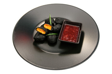 Deep-fried fried cheese with sauce on a black plate