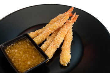 Deep fried shrimp with sauce on a black plate