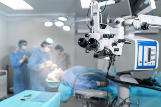 Surgical microscope in operating room with doctors. Ophthalmological clinic. Microsurgical optical equipment