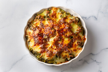 Casserole Cauliflower and broccoli baked with cheese sauce in a pot close-up on a wooden table. Horizontal top view from above. Broccoli gratin.