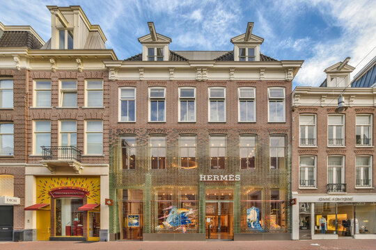 Amsterdam, Netherlands - 10 April, 2021: a building in the middle of an urban area with people walking on the sidewalk, and some buildings behind it
