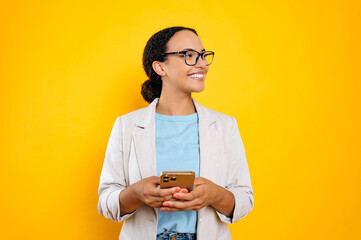 Lovely confident mixed race woman with glasses, stylishly dressed, using mobile phone, chatting in...