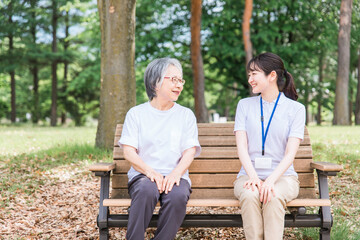 公園で話す高齢者と笑顔で介護スタッフの女性(話し相手・話す・楽しい)
