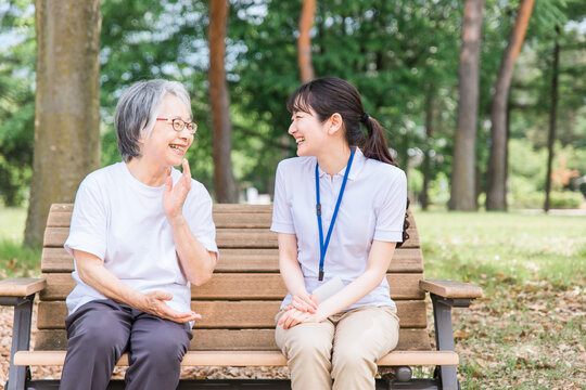 公園で話す高齢者と笑顔で介護スタッフの女性(話す・楽しい)
