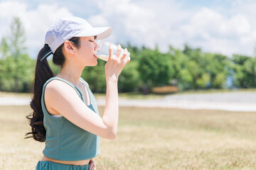 公園でトレーニングしながらプロテインを飲む女性
