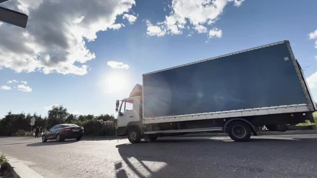 Semi-trailer truck is driving to the logistics park territory with warehouses for unloading and loading on a ramp. Side view