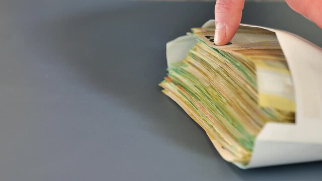 Envelope with money.Hands recalculate banknotes and put in an envelope on a gray background.Slow motion.Expenses and incomes in European countries. 4k footage