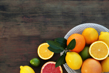 Different citrus fruits and leaves on wooden table, flat lay. Space for text